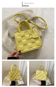Detail of yellow quilted biscuit bag with top handles, long strap and cheese charm