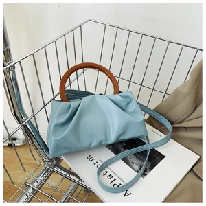 Close-up of light blue pleated cloud bag in a metal cart with brown round handle