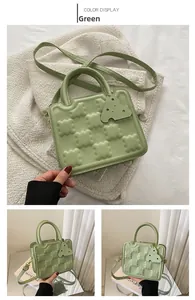 Detail of green square crossbody bag with cookie-style embossing and top handle