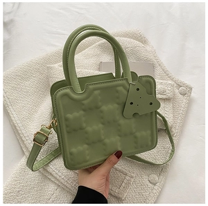 Detail of light green biscuit-shaped handbag with textured surface and cheese charm