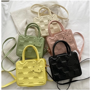 Macro view of textured biscuit-shaped PU leather handbags in five pastel colors