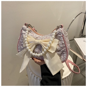 Detail of light pink pleated bag with large white bow and premium pearl handle