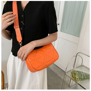 Detail der orangefarbenen Stepptasche mit verstellbarem breitem Stoffgurt am Modell