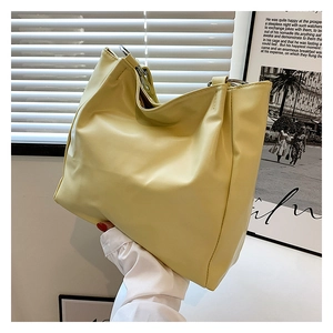 Detail of yellow tote bag with silver metal ring handle and premium stitched leather texture
