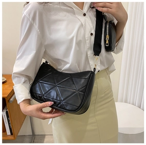 Detail der schwarzen Stepptasche mit geometrischem Muster und kleinem runden Beutel