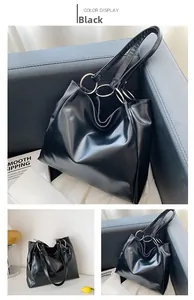 Detail of black tote bag featuring distinctive silver metal ring handle connectors