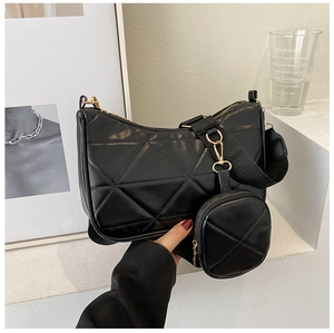 Detail einer schwarzen Stepptasche mit breitem Gurt und kleiner runder Geldbörse