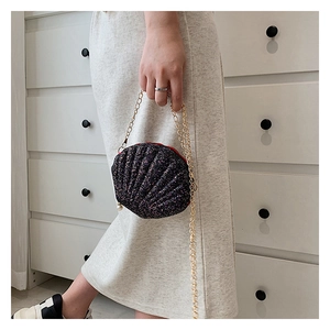 Close-up of glittery shell evening bag with gold chain strap and pearl zipper charm