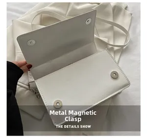 Detail of the high-quality metal magnetic closure on a white minimalist shoulder bag