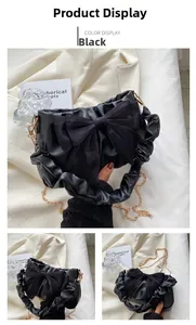 Dettaglio borsa in pelle lucida nera con fiocco decorativo e manico arricciato