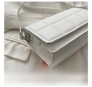 Close-up of white quilted crossbody bag showing precise stitching and silver metal hardware
