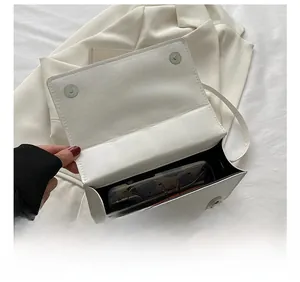 Detail view of the spacious interior of this white crossbody bag with sunglasses inside