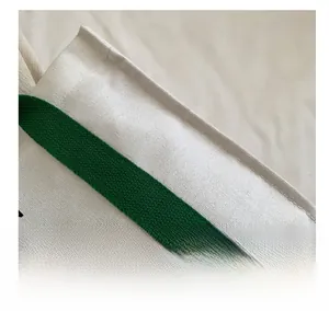 Detail view of reinforced stitching on off-white canvas tote bag with green handles