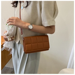 Detail of a brown quilted leather crossbody bag with silver hardware and thin shoulder strap