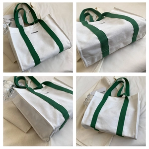 Detail view of large white canvas tote bag with green handles and fashion print