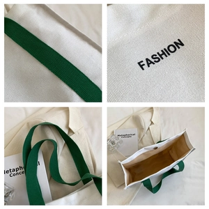 Detail view of canvas tote bag with green handles, fashion embroidery and magnetic closure