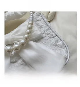 Close-up of white floral textured handbag with a satin bow and pearl bead handle