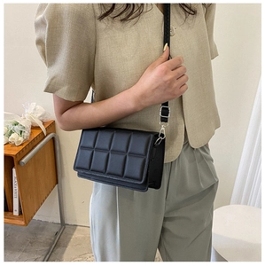 Detail of a black quilted leather crossbody bag with elegant lattice stitching pattern