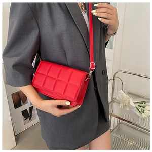 Close-up of red quilted crossbody bag with glossy leather and silver metal buckles