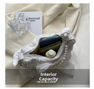 Internal capacity of white floral handbag with bow and pearl strap showing daily items