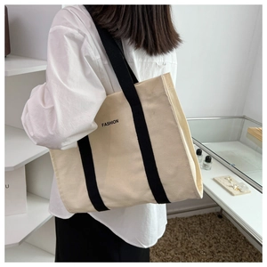 Detail showing the large capacity cream canvas tote with wide black shoulder straps