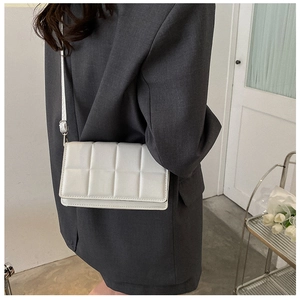 Detail of white checkered quilted crossbody bag with adjustable strap on a model