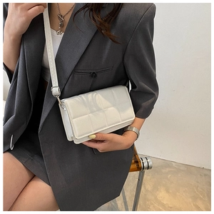 Detailed view of a white padded quilted crossbody bag with stylish silver metal hardware