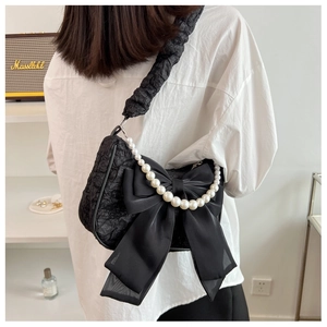 Detail of black pleated shoulder bag with pearl chain and oversized chiffon bow decoration