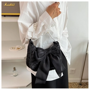 Detail of pleated black cloud bag with large satin bow and white pearl handle strap