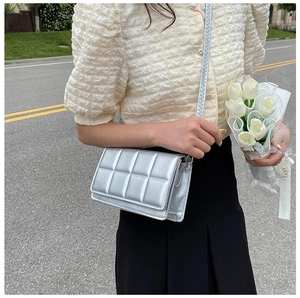 Close-up of a silver padded grid crossbody bag with metallic quilted leather texture