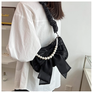 Detailed shot of black floral pleated cloud bag with organza bow and pearl chain