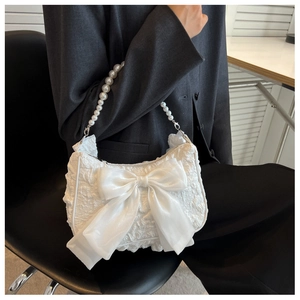 Close-up of white pleated cloud bag with oversized fabric bow and pearl handle