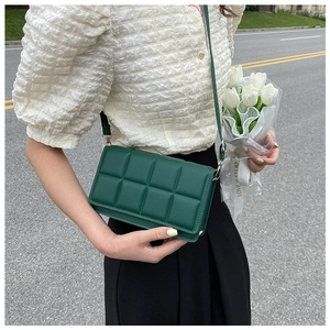 Detail of dark green quilted crossbody bag with 3D plaid texture and adjustable strap