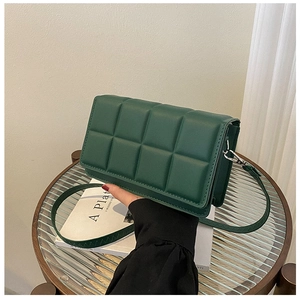 Detail of dark green quilted faux leather crossbody bag with flap and slim strap