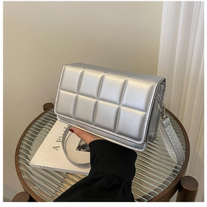 Detail of silver quilted shoulder bag with soft metallic texture and metal hardware
