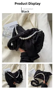 Detail of black pleated cloud bag featuring large bow and white pearl chain strap
