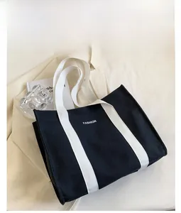 Close-up of black canvas tote bag showing white fashion print and contrasting straps