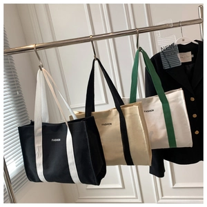 Three minimalist canvas tote bags in various color schemes hanging on a display rack