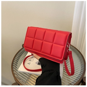 Detail of red padded quilted leather crossbody bag with distinctive grid texture and silver metal hardware