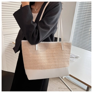 Detail of a large straw tote bag with white leather straps shown on a female model