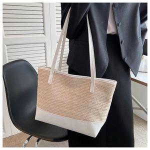 Detail of beige straw texture and white leather handles on large capacity tote bag