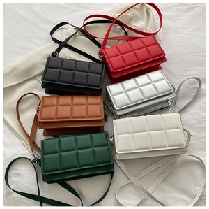 Top-down display of six colors of quilted square crossbody bags on a white fabric surface