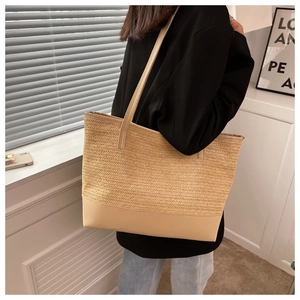 Detail of herringbone woven straw tote bag with reinforced faux leather base and straps
