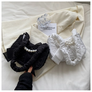 Close-up of ruched cloud bag featuring decorative large bow and elegant pearl handle detail