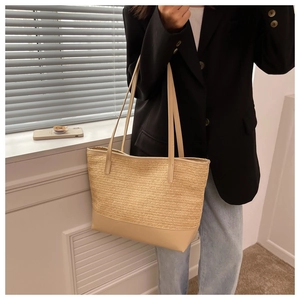 Close-up of woven straw tote bag featuring synthetic leather details and handles