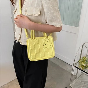 Yellow crossbody biscuit bag with checkerboard texture and cheese charm shown on a model