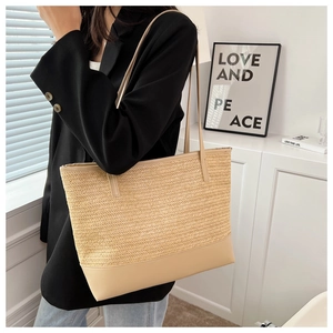 Detail of a large straw tote bag featuring a reinforced smooth base and slim dual straps