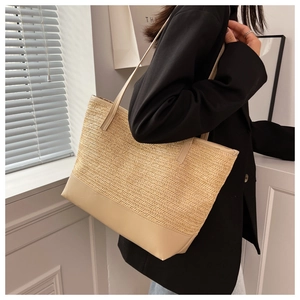 Detailed view of large straw tote bag with herringbone weave and leather base detail