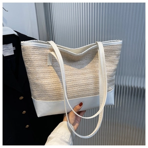 Close-up of woven straw and white leather patchwork tote bag with stitching detail