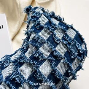 Detailopname van blauw-beige geblokte denimstof met gerafelde randen en textuur